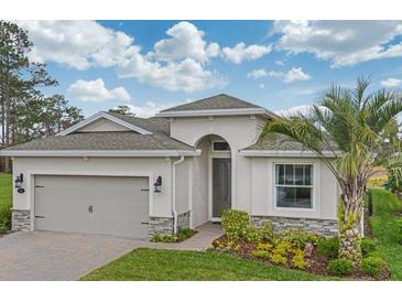 Charming single-story home featuring a two-car garage, stone accents, and a well-maintained lawn at 145 Old Moss Cir, Deland, FL 32724