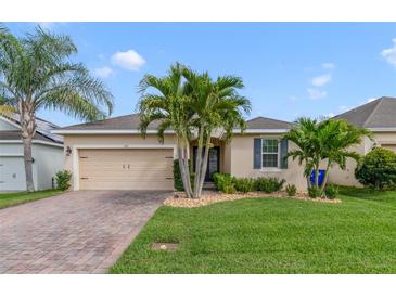 Charming single-story home featuring a brick driveway, lush landscaping, and a two-car garage at 1703 Leatherback Ln, St Cloud, FL 34771