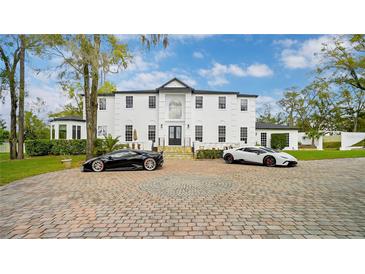 Stunning white two-story home with a circular driveway and two luxury sports cars at 1943 Wingfield Dr, Longwood, FL 32779