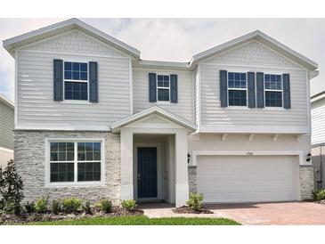 Charming two-story home with gray stone accents, a two-car garage, and a neatly landscaped front yard at 1988 Iorio Dr, St Cloud, FL 34771