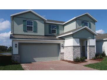 Charming two-story home featuring a gray garage door, stone accents, and lush lawn at 2006 Iorio Rd, St Cloud, FL 34771