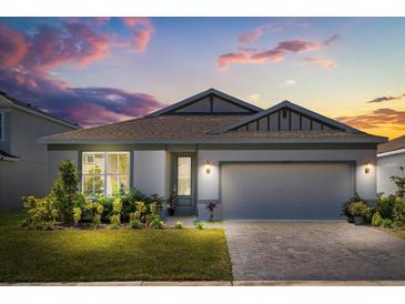 Charming home with a gray exterior, brick driveway, well-manicured lawn and beautiful decorative plants at 5058 Sparkling Water Way, Kissimmee, FL 34746