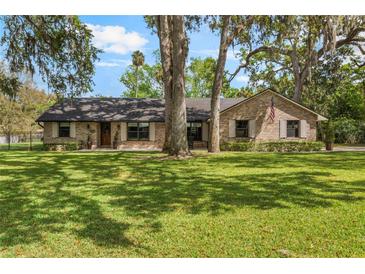 Charming brick home featuring a well-manicured lawn and mature trees offering shade at 598 Palm Dr, Oviedo, FL 32765