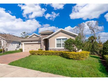 Charming single-story home boasts a well-manicured lawn, brick driveway and stone accents at 6097 Monterey Cypress Trl, Sanford, FL 32773