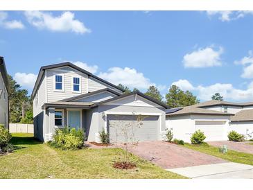 Charming two-story home featuring gray siding, a brick driveway, and a light blue front door at 869 Rivers Crossing St, Clermont, FL 34714
