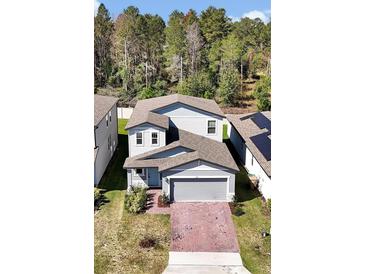 Charming two-story home with a well-manicured lawn and brick driveway, complemented by mature trees at 869 Rivers Crossing St, Clermont, FL 34714