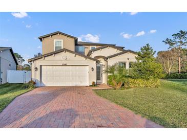 Inviting two-story home with a manicured lawn, brick driveway, and attached two-car garage at 2940 Scarlett Dr, St Cloud, FL 34772