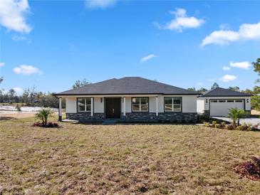 Charming single-story home featuring a modern exterior, stone accents, and a detached garage at 31905 Larkspur Ave, Eustis, FL 32736