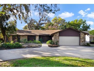 Charming single-story home with stone accents, mature landscaping, and an attached two-car garage at 342 Oak Estates Dr, Orlando, FL 32806