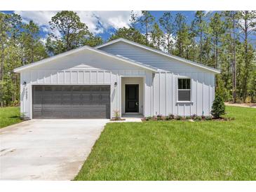 Charming single-story home with a well-manicured lawn and a gray garage door, surrounded by lush trees at 7007 Sw 131St Ave, Ocala, FL 34481