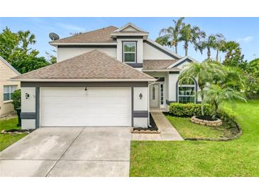 Two-story home featuring an attached two-car garage, mature landscaping, and tropical palm trees at 3408 Idlegrove Ct, Orlando, FL 32822