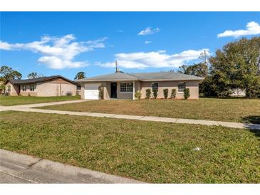 Charming single-story home with well-maintained lawn and attached one car garage, under a bright blue sky at 4207 Chateau Rd, Orlando, FL 32808