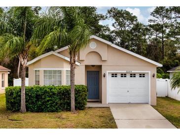 Charming home featuring a one-car garage and blue front door, complemented by lush landscaping at 2209 Hannah Ln, Orlando, FL 32826