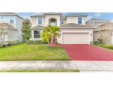 Charming two-story home featuring a manicured lawn, vibrant landscaping, and a red brick driveway leading to an attached garage at 2246 Rush Bay Way, Orlando, FL 32824