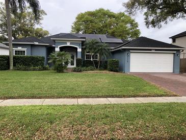 Charming blue single-story home with well-manicured lawn, trimmed shrubs and solar panels at 4024 Lillian Hall Ln, Orlando, FL 32812