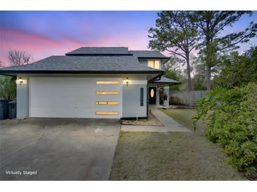 Two-story home featuring a gray exterior, dark roof, and a modern garage door with horizontal window accents at 4086 Biscayne Ct, Casselberry, FL 32707