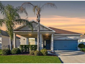 Charming single-story home featuring a well-manicured lawn, mature palm trees, and an inviting facade at sunset at 5571 Sycamore Canyon Dr, Kissimmee, FL 34758