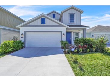 Charming two-story home with a well-manicured lawn, two-car garage, and eye-catching blue door at 659 Daring Dr, Davenport, FL 33837