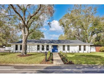 Charming one story home with a blue door, landscaped yard, and mature trees at 1536 Errol Pkwy, Apopka, FL 32712