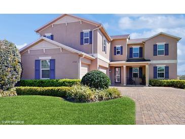 Charming two-story home with a well-manicured lawn, beautiful shrubbery, and brick driveway at 1722 Lake Sims Pkwy, Ocoee, FL 34761