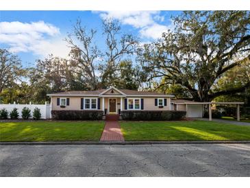 Charming home featuring a manicured lawn, brick walkway, and complemented by mature trees at 1818 S Oak Ave, Sanford, FL 32771