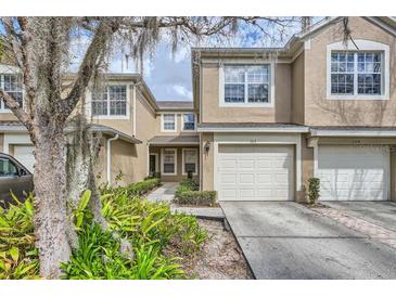 Charming townhome featuring an attached garage, manicured landscaping, and a welcoming facade at 2847 Metro Sevilla Dr # 103, Orlando, FL 32835