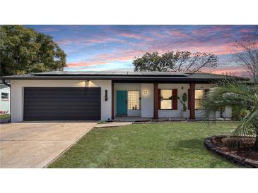 Inviting single-story home with a well-manicured lawn, modern solar panels, and a vibrant blue front door at 48 Carriage Hill Cir, Casselberry, FL 32707