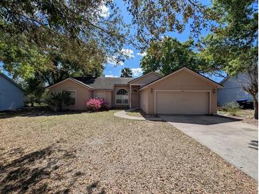 Charming single-story home with mature trees, a two-car garage, and a well-maintained front yard at 8040 Equitation Ct, Orlando, FL 32818