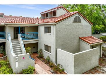 Charming two-story condo features a red tile roof, stucco exterior, and a welcoming blue railing at 1000 Winderley Pl # 237, Maitland, FL 32751