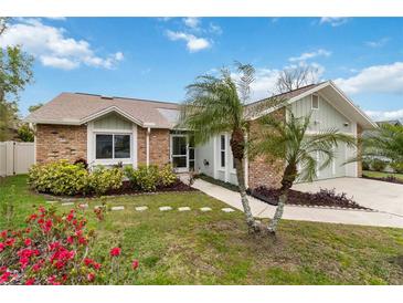 Charming brick home with a well-manicured lawn, landscape and mature palm trees at 1071 Sweet Tree Ct, Apopka, FL 32712