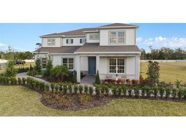 Beautiful two-story home featuring a manicured lawn, lush landscaping, and charming front porch seating at 2141 Weatherly Way, Orlando, FL 32820
