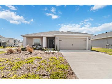 Charming single-story home featuring a two-car garage and well-maintained landscaping with a stone covered yard at 5996 Wildflower Field Way, St Cloud, FL 34771