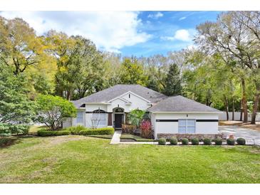 Charming single-story home with manicured lawn, mature trees, and inviting curb appeal during daytime at 8176 Emerald Forest Ct, Sanford, FL 32771