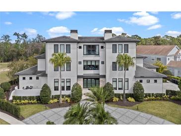 Stately three-story home featuring a manicured front yard and a paver circular driveway at 1297 Grand Traverse Pkwy, Reunion, FL 34747