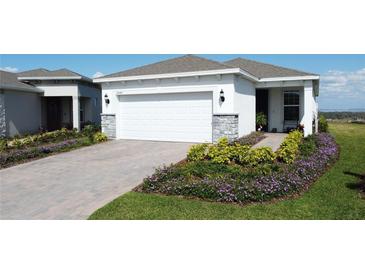 Charming single Gathering home with a two-car garage, decorative stone accents, and beautiful landscaping at 2842 Purple Meadow Ct, Minneola, FL 34715