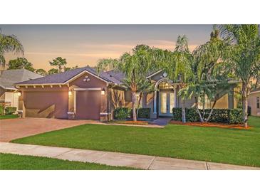 Charming home featuring a well-manicured lawn, mature palm trees, and a welcoming arched entryway at 3734 Safflower Terrace, Oviedo, FL 32766