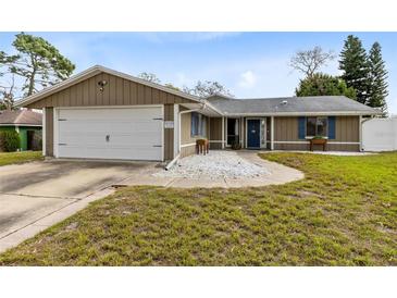 Charming single-story home featuring a two-car garage and quaint front yard with decorative rock and blue shutters at 409 Surrey Run, Casselberry, FL 32707