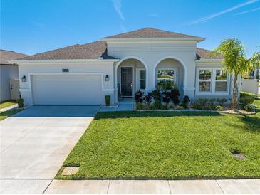 Charming one-story home featuring arched entryway, lush lawn, and attached two-car garage at 5301 Amersham Ln, St Cloud, FL 34771