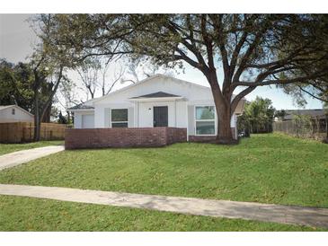 Charming single-story home featuring a well-manicured lawn, a brick accent wall and a large shade tree at 6222 Fox Hunt Trl, Orlando, FL 32808