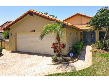 Charming exterior featuring a two-car garage, tiled roof, well-maintained landscaping, and a secure ADT system at 6552 Edgeworth Dr, Orlando, FL 32819