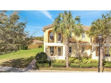 Charming two-story home with a yellow exterior, red tile roof, balcony, and lush landscaping at 12016 Lorenza Ln, Orlando, FL 32827