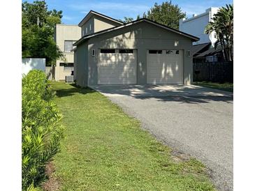 Large two-car garage featuring an extended driveway and lush landscaping at 1213 Richmond Rd, Winter Park, FL 32789