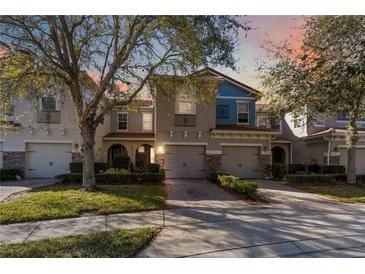 Charming townhome featuring a well-maintained lawn, two-car garage, and lovely architectural details at 124 Canterbury Bell Dr, Oviedo, FL 32765