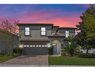 Charming two-story home featuring a brick driveway, gray stucco, and a tile roof at 1412 Moon Valley Dr, Davenport, FL 33896