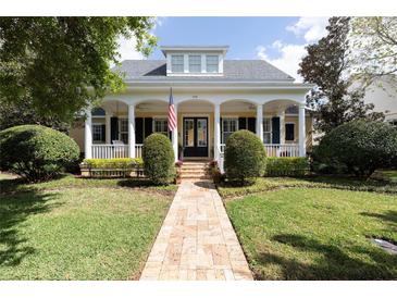 Charming two-story home with a welcoming front porch, beautiful landscaping, and a brick walkway at 2161 Snow Rd, Orlando, FL 32814