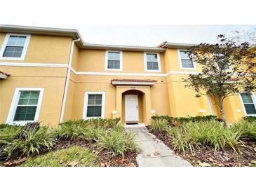 Inviting townhome featuring a well-manicured front yard and a bright, yellow exterior at 3018 Red Ginger Rd, Kissimmee, FL 34747