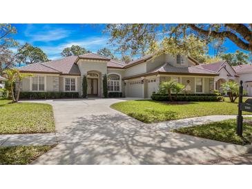 Stunning home featuring a barrel tile roof, a well manicured lawn and mature landscaping at 3369 Park Grove Ct, Longwood, FL 32779