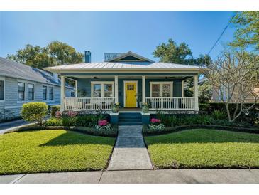 Charming home featuring a beautifully landscaped yard and inviting covered porch with a bright yellow front door at 428 Highland Ave, Orlando, FL 32801