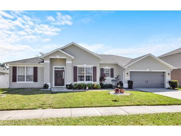 Charming single-story home features a manicured lawn, two-car garage, and welcoming front entrance with decorative accents at 2168 Continental St, St Cloud, FL 34769