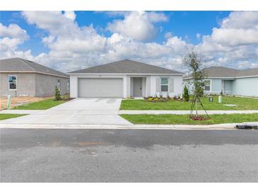 Charming single-story home with a neutral color scheme, well-manicured lawn, and a two-car garage at 304 Towns Cir, Haines City, FL 33844